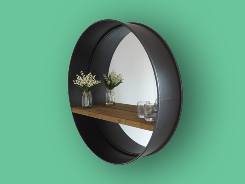 Large round industrial metal wall mirror with rustic wood shelf.